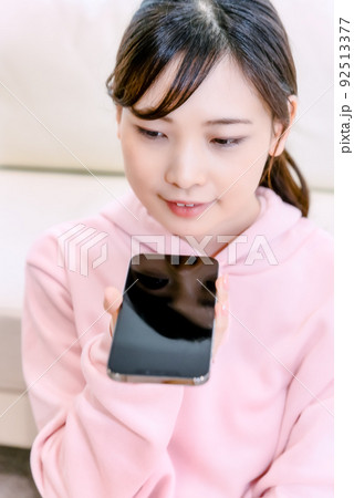 音声入力でスマホを操作する若い女性 92513377