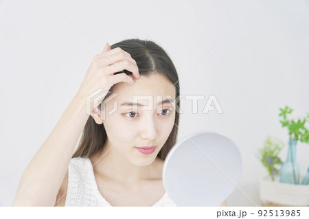 リビングで鏡で髪の毛をチェックする女性 92513985