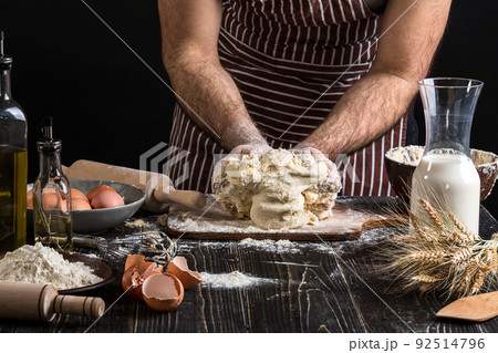 Against the background of men's hands knead the dough. Ingredients for cooking flour products or dough bread, muffins, pie, pizza dough . 92514796