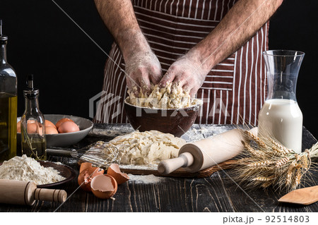 Against the background of men's hands knead the dough. Ingredients for cooking flour products or dough bread, muffins, pie, pizza dough . 92514803