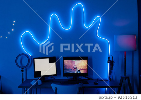 Horizontal image of dark room decorated with neon light and computer monitors on table for video game 92515513