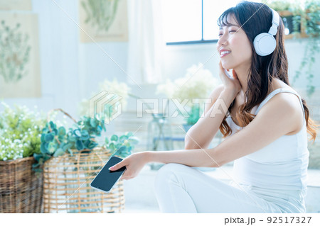 ヘッドフォンでスマホの音楽を聴く若い女性 92517327