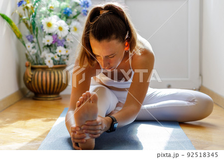 Young woman stretching legs during her morning yoga training Young woman stretching legs during her morning yoga training 92518345