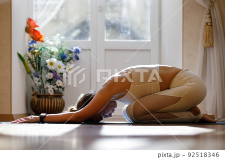 Young yoga woman resting in child pose on the mat during her yoga routine Young yoga woman resting in child pose on the mat during her yoga routine 92518346