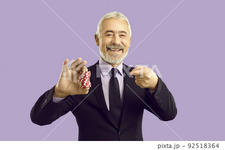 Smiling mature man point at casino chips Smiling mature man point at casino chips 92518364