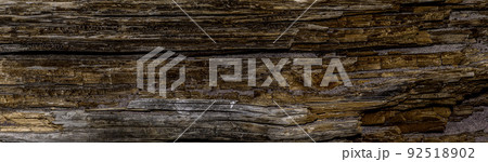 Panorama of an old dark rough wood floor or surface with splinters and knots. Horizontal parallel decking or boards with a wood texture. Panorama of an old dark rough wood floor or surface with splinters and knots. Horizontal parallel decking or boards with a wood texture. 92518902