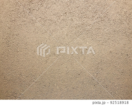 明るい茶色の土壁のなかに藁の粗い風合いが残る表面の横長の背景画像 92518918