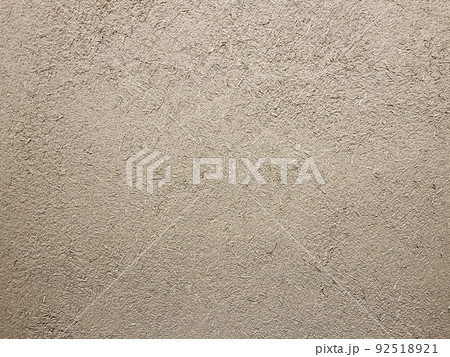 明るい薄茶色の土壁のなかに藁の粗い風合いが残る表面の横長の背景画像 92518921