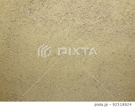 明るい砂色の土壁のなかに藁の粗い風合いが残る表面の横長の背景画像 92518924