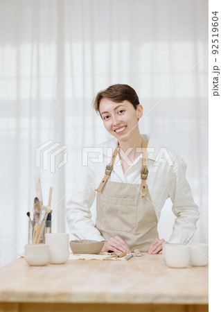 woman ceramist in the workshop makes mugs out of clay. small business or hobby is the creation of ceramic products woman ceramist in the workshop makes mugs out of clay. small business or hobby is the creation of ceramic products 92519604