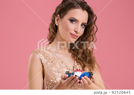 Smiling girl holding a gambling chips in her nands on pink background Smiling girl holding a gambling chips in her nands on pink background 92520645