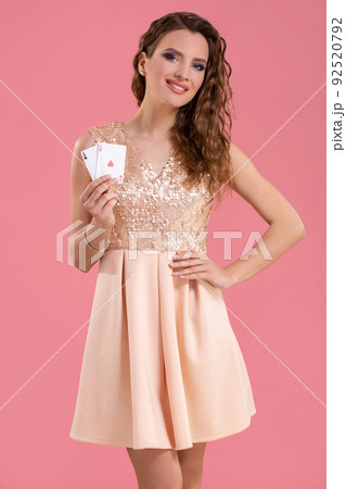 Young beautiful woman holding the winning combination of poker cards on pink background. Two aces 92520792