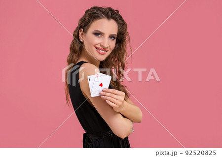 Young woman holding two aces in hand against on pink background Young woman holding two aces in hand against on pink background 92520825