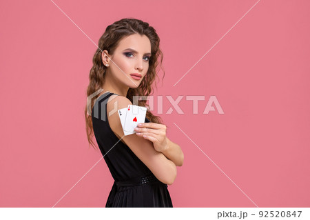 Young woman holding two aces in hand against on pink background Young woman holding two aces in hand against on pink background 92520847