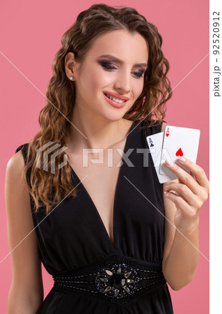 Young woman holding two aces in hand against on pink background 92520912
