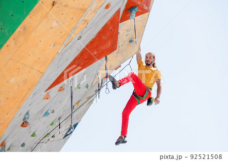 Sportsman climber moving up on steep rock, climbing on artificial wall. 92521508