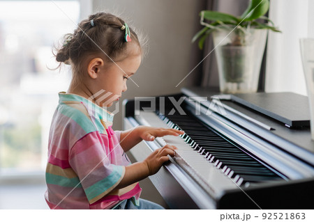 Side view of cute asian girl playing piano at home 92521863
