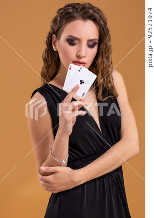 Beautiful brown-haired woman holding two aces as a sign for poker game, gambling and casino Beautiful brown-haired woman holding two aces as a sign for poker game, gambling and casino 92521974