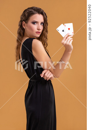 Beautiful brown-haired woman holding two aces as a sign for poker game, gambling and casino Beautiful brown-haired woman holding two aces as a sign for poker game, gambling and casino 92522040