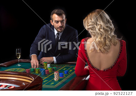 A beautiful young woman and a man are sitting at a roulette table. Casino. 92522127
