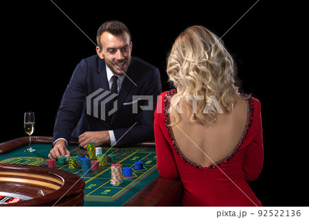 A beautiful young woman and a man are sitting at a roulette table. Casino. 92522136