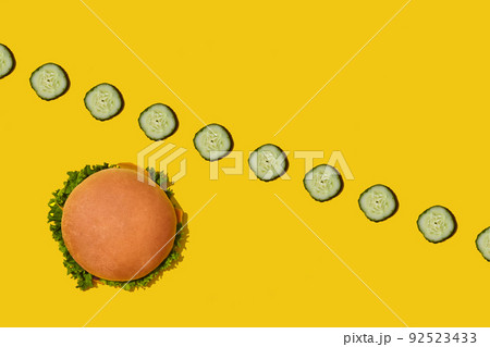 Tasty fresh unhealthy hamburger with ketchup and vegetables on yellow vibrant bright background. Top View with Copy Space. 92523433