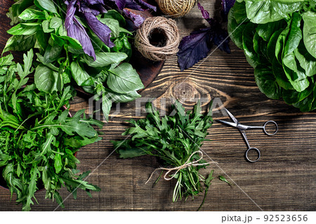 Variety of fresh organic herbs on wooden background. Freshly harvested herbs including basil, arugula. Top view. Copy space. 92523656