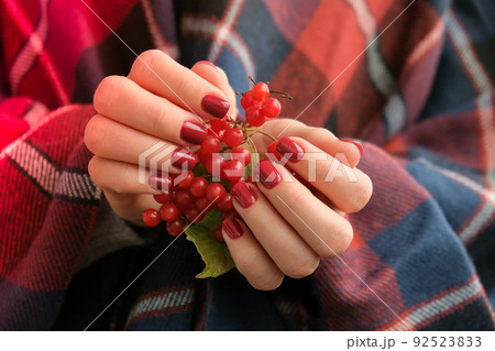 Stylish red female nails. Hands Holding Red Currants. Modern Beautiful manicure. Autumn winter nail design concept of beauty treatment. Gel nails. Skin care. Stylish red female nails. Hands Holding Red Currants. Modern Beautiful manicure. Autumn winter nail design concept of beauty treatment. Gel nails. Skin care. 92523833
