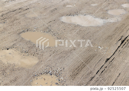a dirt road with a lot of water holes 92525507