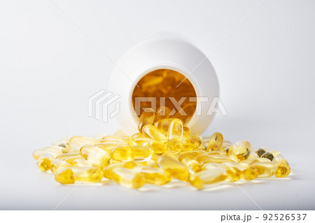 Yellow fish oil capsules in a jelly shell near the white jar Yellow fish oil capsules in a jelly shell near the white jar 92526537