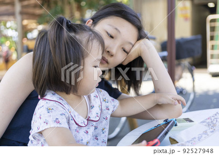 ゲームをする幼児とそれを見る姉 92527948