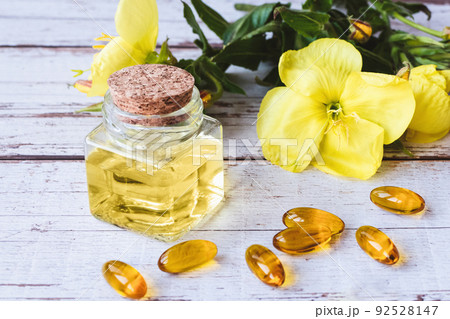 Evening primrose oil in bottle, softgels and flowers on wooden table Evening primrose oil in bottle, softgels and flowers on wooden table 92528147