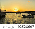 碇泊する漁船の間に沈む夕日が波間にきらめく茅ヶ崎漁港の夕景 92528607