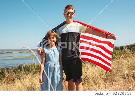 Happy smiling kids with america flag outdoors on a sunny summer day. 92529215