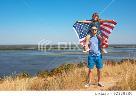 Happy family father and child with usa flag enjoying nature. Free lifestyle 92529230