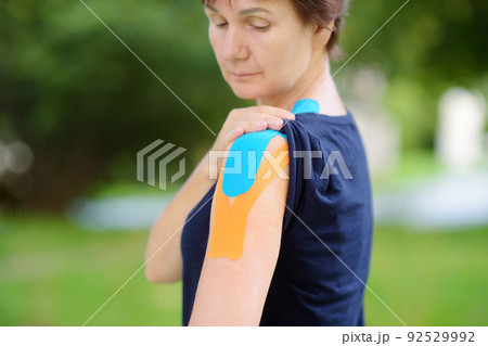 Woman with kinesio tape on her shoulder. Kinesiology, physical therapy, rehabilitation Woman with kinesio tape on her shoulder. Kinesiology, physical therapy, rehabilitation 92529992