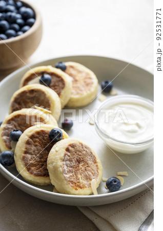 Cottage cheese fritters, ricotta pancakes with sour creamand bleberries. Healthy food. Warm background 92531771