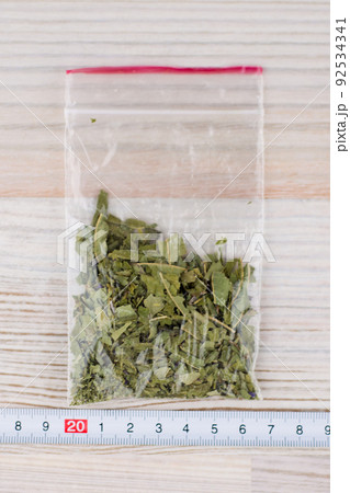 expert analysis of the contents of the package, with material evidence, the suspected presence of drugs, the package of stuff is on the table next to a ruler vertically 92534341