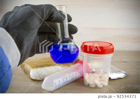 the laboratory assistant of the customs laboratory shows a flask with a positive test result for opiate content in samples, a short focus, vignetting 92534371