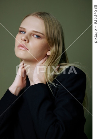 The head portrait of a charming beautiful girl in a black jacket poses on a green background in the studio. Cool banner for brands. Cool offer for design 92534588