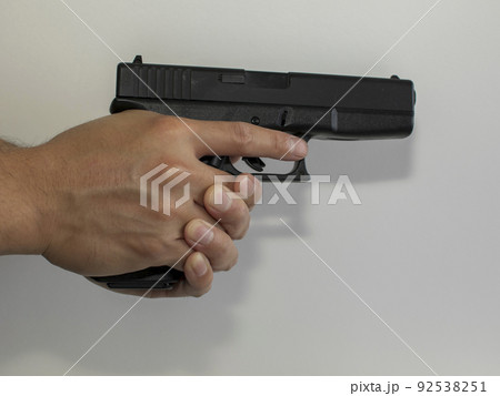 ホワイトバックで拳銃（エアガン）を両手で構える様子 92538251