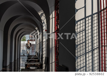 At evering the light though perforated sheet steel. Sun shinning down at a woman against the wall. At evering the light though perforated sheet steel. Sun shinning down at a woman against the wall. 92538602