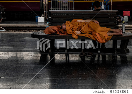 A monk is sleep on wooden chairs are waiting for trains in the area provided at Main railway station of Hua Lamphong. A monk is sleep on wooden chairs are waiting for trains in the area provided at Main railway station of Hua Lamphong. 92538861