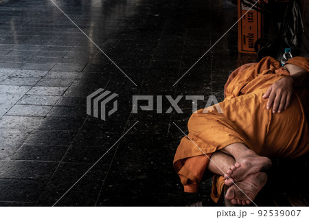 A monk is sleep on wooden chairs are waiting for trains in the area provided at Main railway station of Hua Lamphong. 92539007