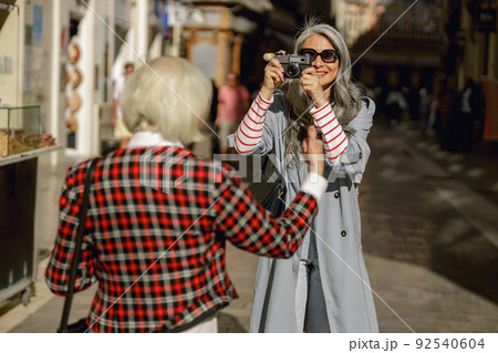 Enthusiastic lady with camera taking photos on street 92540604