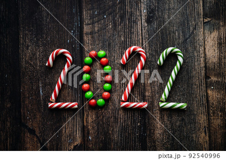 Year 2022 laid out from round multicolored candies and candy canes on wooden background 92540996
