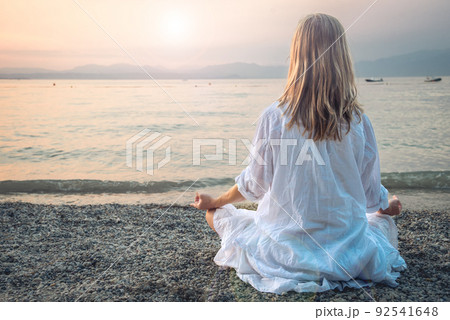 Woman meditating at the Garda Lake. Sunset. Woman meditating at the Garda Lake. Sunset. 92541648