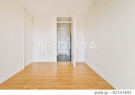 Interior of empty modern apartment with geometric design with entrance door and white walls and parquet floor illuminated with lamp 92542892
