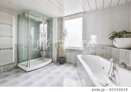 Luxurious bathroom interior design with marble walls, glass shower, corner bathtub, clothes dryer, plants and window Luxurious bathroom interior design with marble walls, glass shower, corner bathtub, clothes dryer, plants and window 92543629