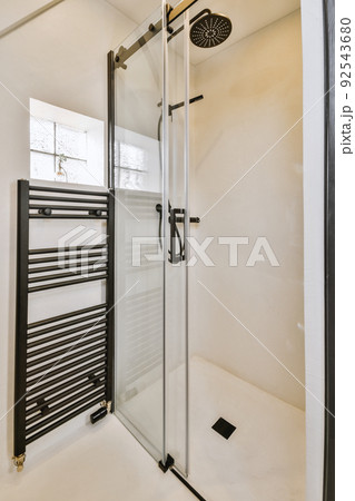 Shower faucets attached to tiled wall near glass partition and ornamental curtail in washroom at home Shower faucets attached to tiled wall near glass partition and ornamental curtail in washroom at home 92543680